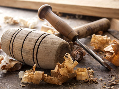 Ein Holzklotz, ein Schnitzwerkzeug und Holzspäne auf einer Werkbank.